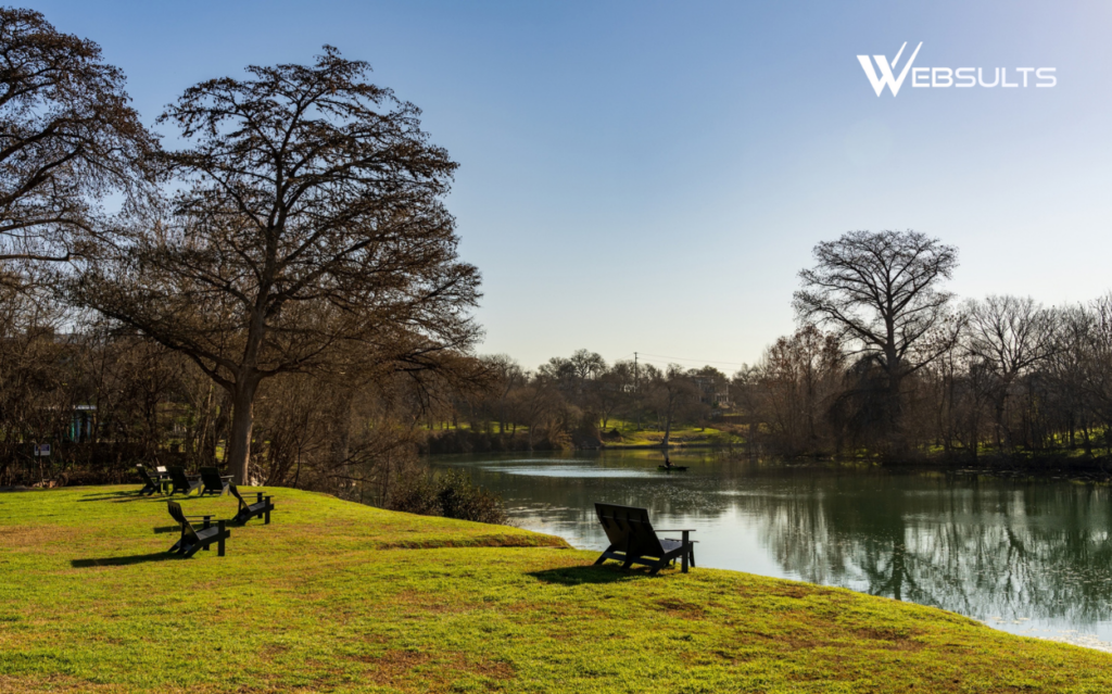 Riverfront park in New Braunfels, Texas, with lawn chairs beneath large trees