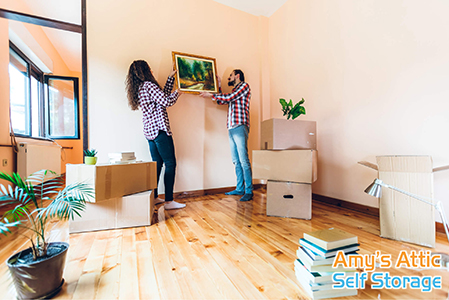 excited couple hangs painting in new home